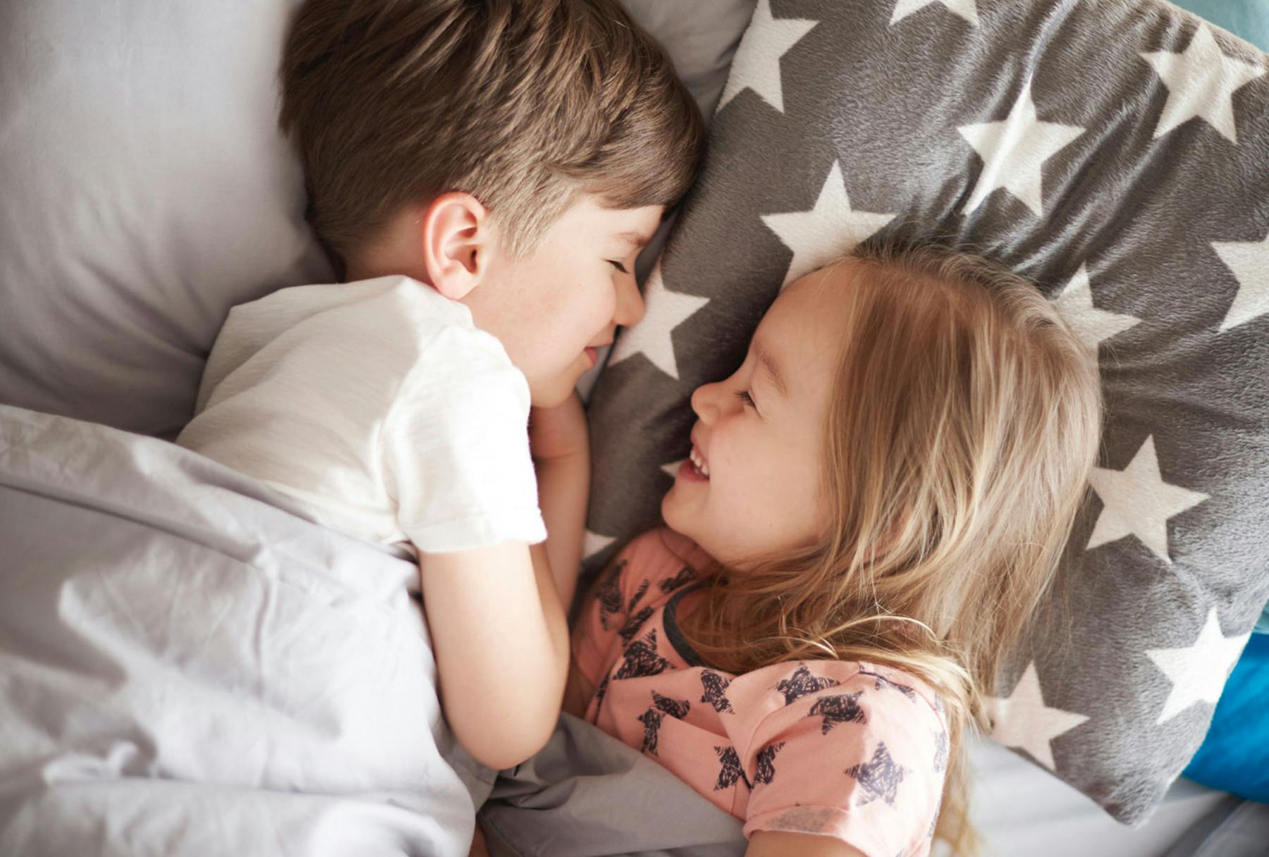 Сын с сестрой занимаются. Детский поцелуй в кровати. Мальчик с девочкой в постели.
